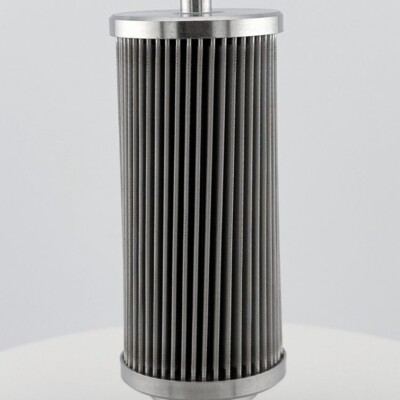 A cylindrical metal industrial filter with vertical pleats, shown upright on a plain white surface.