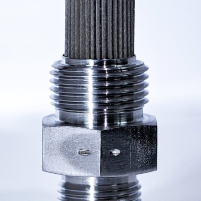 Close-up of a metal hydraulic filter with threaded ends and a cylindrical mesh filter at the top against a white background.