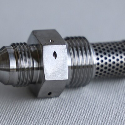 A metal hydraulic fitting with a hexagonal center and a perforated cylindrical filter on one end.